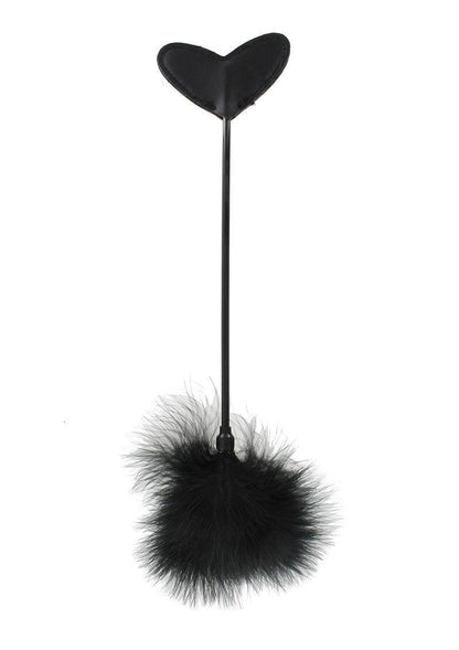 Black heart-shaped leather paddle with a long handle and a fluffy feather end on white background
